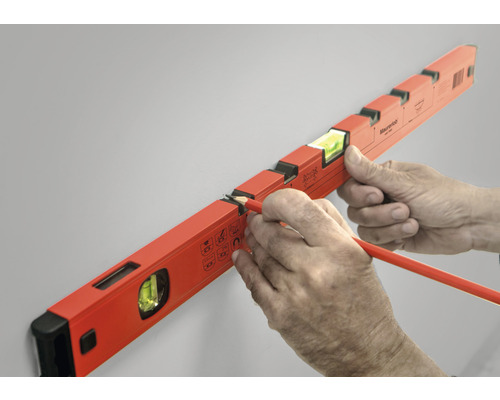 Eine Wasserwaage wird mit einem Stift an einer Wand ausgerichtet.