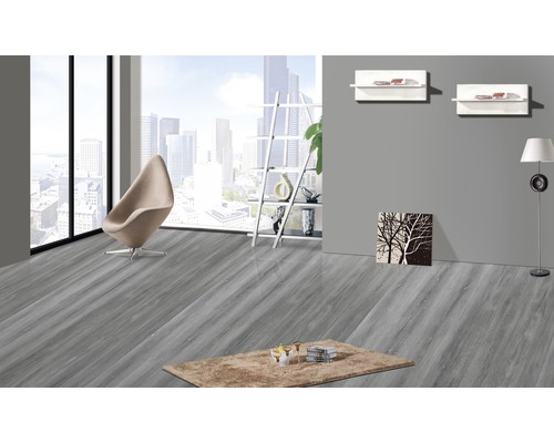 Heller Raum mit grauem Holzboden, Sessel und Teppich