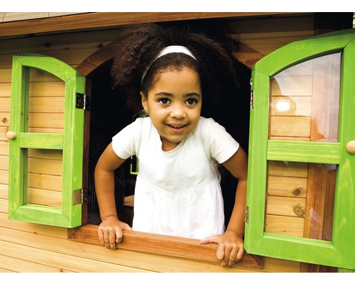 Ein Kind schaut aus dem Fenster eines Holzspielhauses.