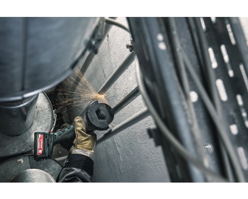 Eine Person benutzt einen Akku-Winkelschleifer zum Schneiden eines Metallrohrs, wobei Funken entstehen.