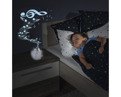 Enfant dormant dans un lit avec projection de boîte à musique sur le mur.