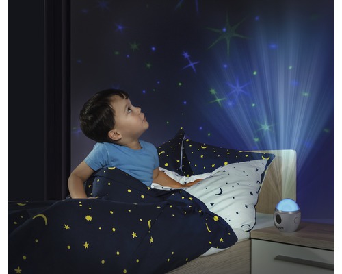 Garçon dans son lit regardant un projecteur de ciel étoilé sur le mur.