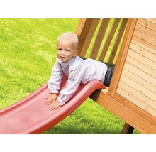 Enfant glissant sur un toboggan d''une cabane de jeu dans le jardin