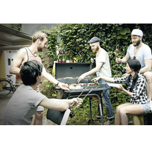 Un groupe d''amis fait des grillades dans le jardin avec un barbecue au charbon de bois et profite du temps passé ensemble.