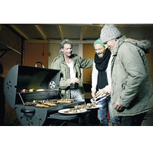 Trois hommes se tiennent autour d''un barbecue avec de la viande, des légumes et des brochettes.
