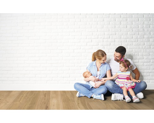 Eine Familie sitzt vor einer Wand aus Ziegelsteinen auf einem Holzboden.