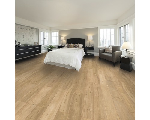 Schlafzimmer mit Holzboden, Bett, Kommode und Sessel.