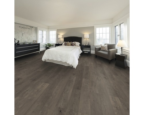 Schlafzimmer mit Bett, Kommode, Sessel und Bodenbelag in Holzoptik