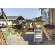 Scène avec une table de pique-nique en bois, des coussins et un chauffage devant des tentes