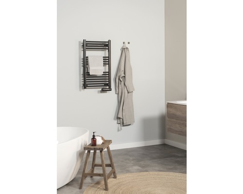 Salle de bains avec sèche-serviettes, serviette, peignoir, tabouret et baignoire