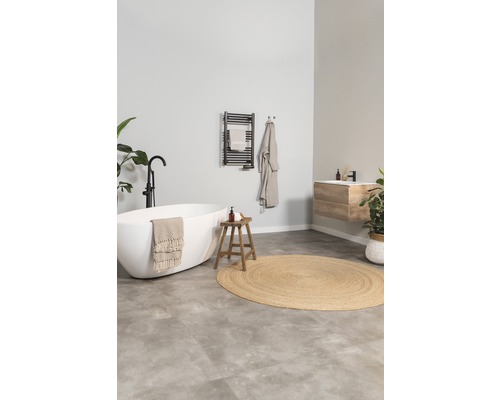 Salle de bains lumineuse avec baignoire îlot, tabouret en bois et radiateur