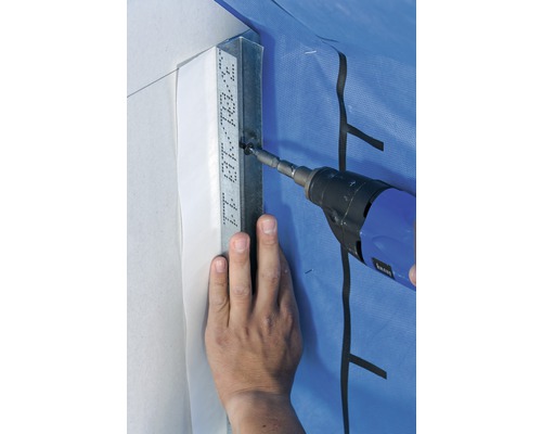 Une personne fixe un rail métallique à un mur à l''aide d''une visseuse sans fil.