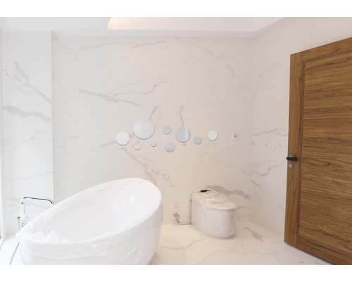 Modernes Badezimmer mit freistehender Badewanne, Toilette und runden Spiegeln als Dekoration