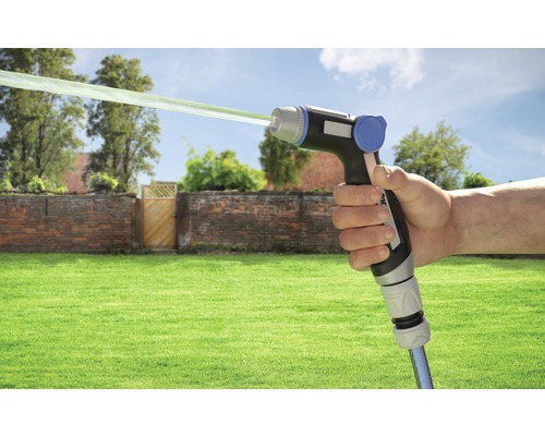 Main tenant un pistolet d''arrosage avec jet d''eau devant un jardin