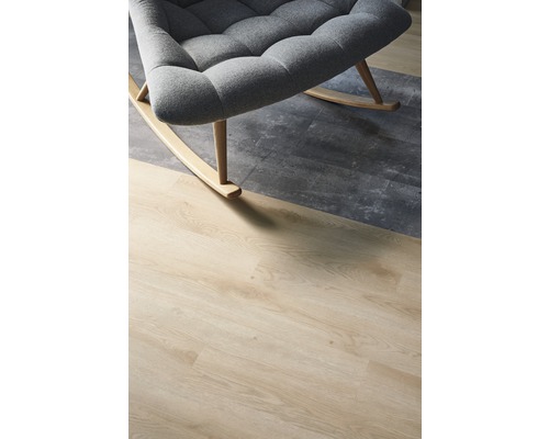 Gros plan d''un fauteuil à bascule gris sur un revêtement de sol aspect bois et béton.