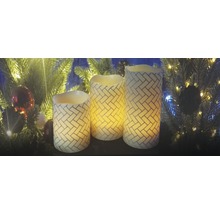 Trois bougies LED décoratives avec un motif de briques devant un arbre de Noël