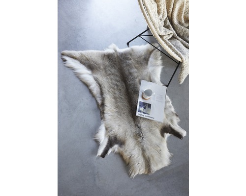 Peau de renne décorative sur le sol à côté d''une chaise et d''un magazine.