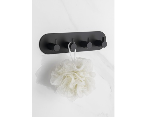 Schwarze Wandgarderobe mit vier Haken und Badeschwamm an einer Marmorwand