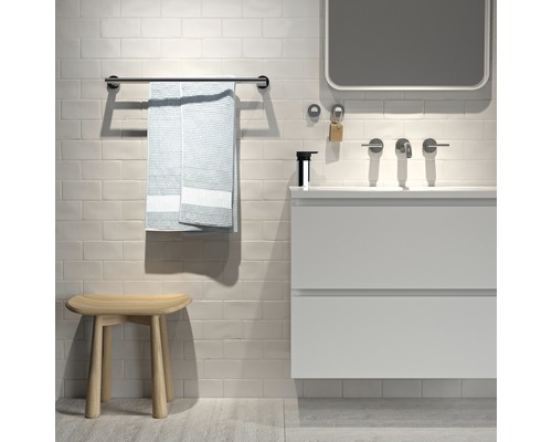 Salle de bains moderne avec meuble-lavabo, miroir, porte-serviettes, serviette et tabouret.