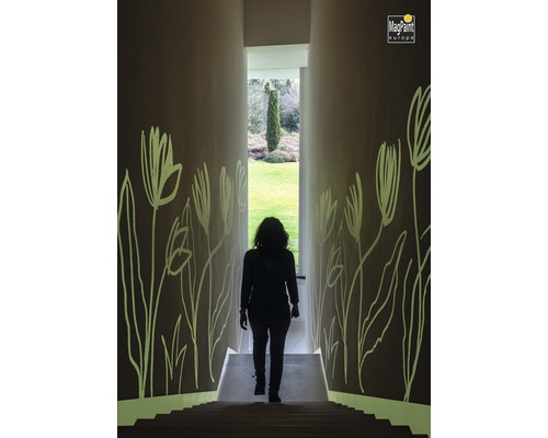 Femme descendant les escaliers dans un couloir avec des motifs floraux sur les murs. Logo MagPaint Europe.