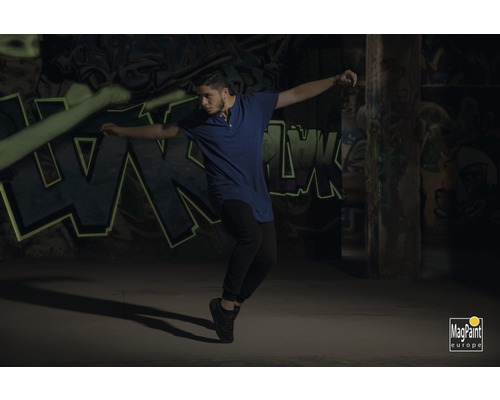 Un homme danse devant un mur avec des graffitis. Logo MagPaint Europe.