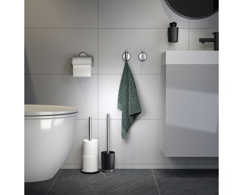 Salle de bains moderne avec toilettes, lavabo, serviette, porte-papier hygiénique et brosse de toilette