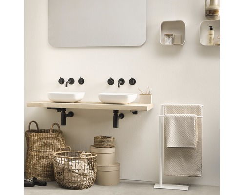 Salle de bains avec double vasque, plateau en bois et porte-serviettes.