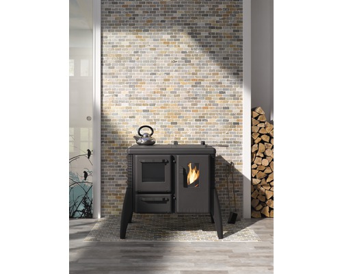 Innenaufnahme mit einem Ofen, einem Teekessel, Brennholz und einer gemauerten Wand