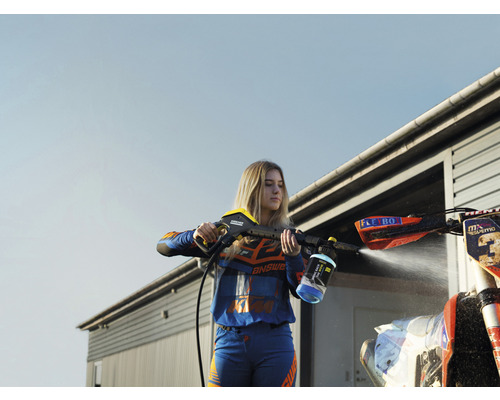 Frau reinigt ein Motorrad mit einem Hochdruckreiniger.