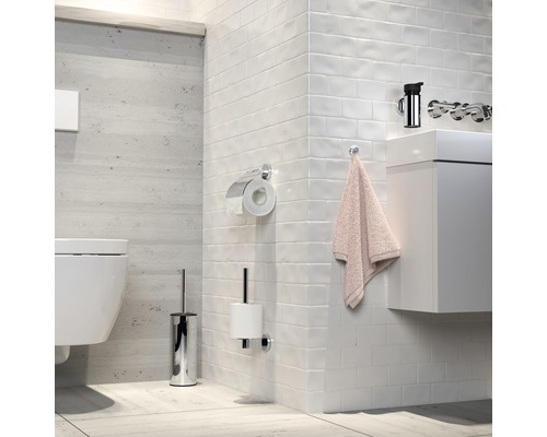 Salle de bains moderne avec WC, lavabo, robinetterie, support papier toilette et ensemble brosse de toilette.
