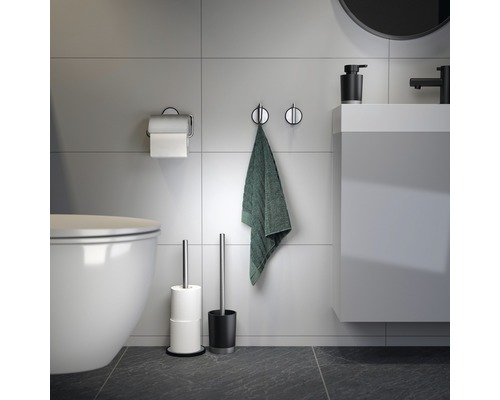 Salle de bains moderne avec toilettes, lavabo, crochets pour serviettes, serviette, porte-papier toilette et brosse de toilette