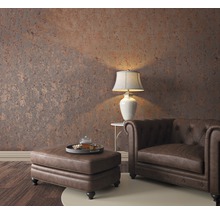 Wohnzimmer mit Chesterfield-Sessel, Ottomanen, Tischlampe und gemusterter Tapete für ein gemütliches Ambiente