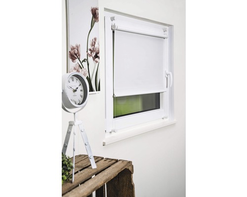 Fenêtre avec store enrouleur blanc, horloge et décoration florale