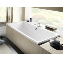 Baignoire rectangulaire dans une salle de bains avec robinetterie et serviettes