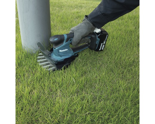 Person benutzt einen Makita Akku-Rasentrimmer, um Gras zu schneiden.