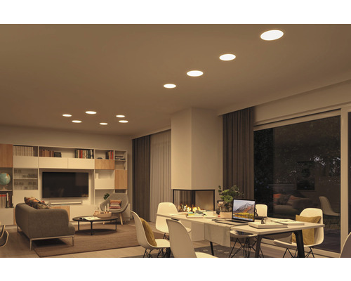 Wohnzimmer mit Deckenleuchten, Sofa, Tisch und Regalen.