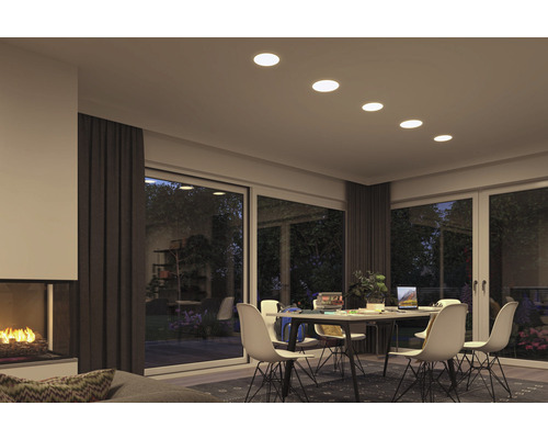 Wohnzimmer mit Kamin, Esstisch, Stühlen und Deckenleuchten