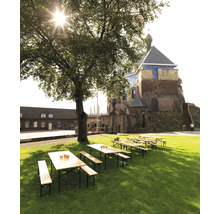 Scène de jardin de bière avec tables et bancs en bois sur une pelouse devant un château