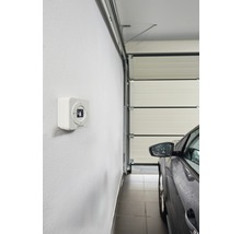 Vue intérieure d''un garage avec porte de garage, voiture et ouvre-porte de garage au mur.