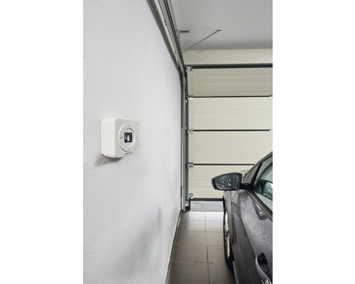 Vue intérieure d''un garage avec porte de garage, voiture et ouvre-porte de garage au mur.