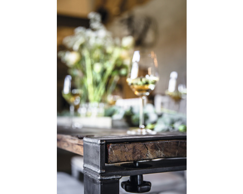 Vue détaillée d''une table avec pieds en métal, plateau en bois, décorations florales et verres à vin