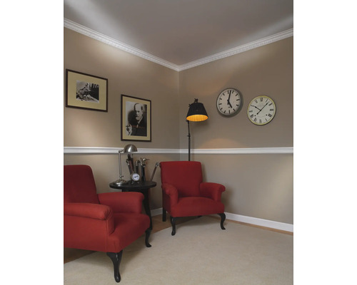 Klassisch eingerichtetes Wohnzimmer mit zwei roten Sesseln, Bildern und Uhren an der Wand