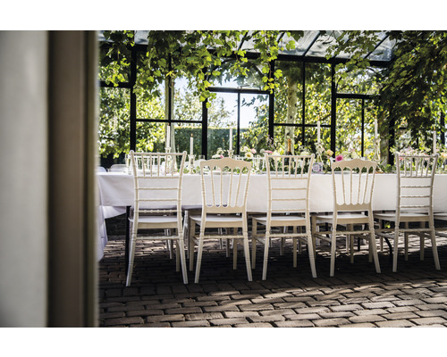 Gedeckte Tafel mit Stühlen in einem Wintergarten