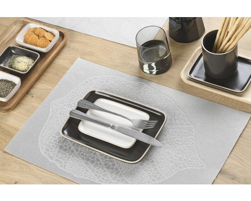 Tischgedeck mit Platzsets, Geschirr, Besteck, Getränken und Snacks auf einem Holztisch