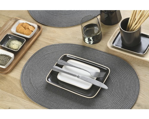 Tischdekoration mit Platzsets, Geschirr, Besteck, Gläsern und Speisen auf einem Holztisch.