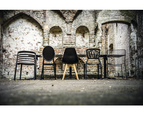 Diverses chaises et une table devant un mur de briques