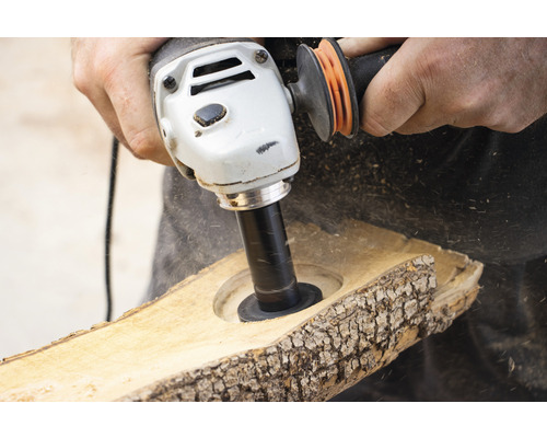 Nahaufnahme einer Person, die mit einer Schleifscheibe ein Loch in ein Holzstück schleift