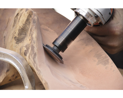 Ein Elektrowerkzeug schleift ein Stück Holz, das mit einer Klemme befestigt ist.