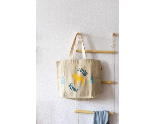 Stofftasche mit Pferdemotiv hängt an einer Holzleiter an der Wand