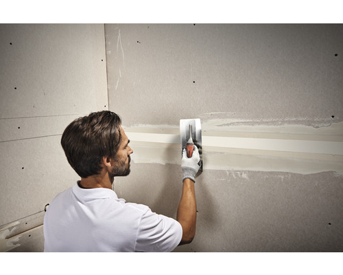 Handwerker verspachtelt eine Gipskartonwand mit einem Spachtel